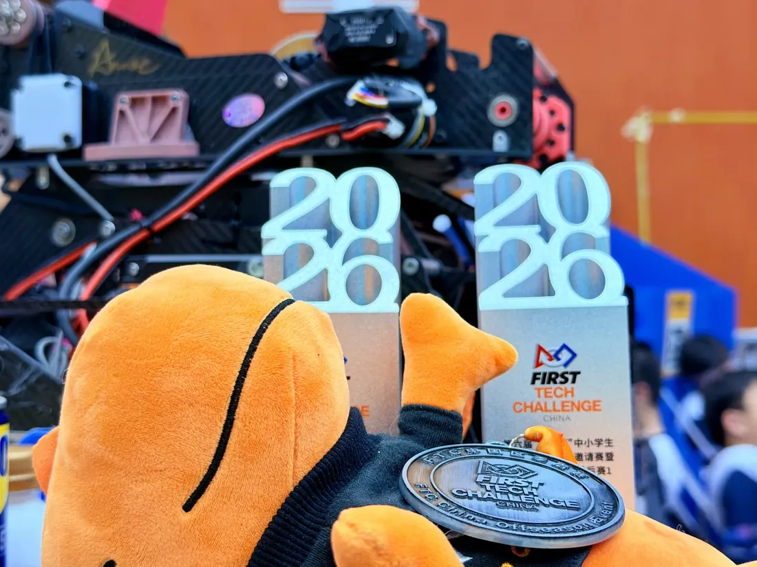 Team mascot in front of the 2026 FIRST Tech Challenge China trophies and medal