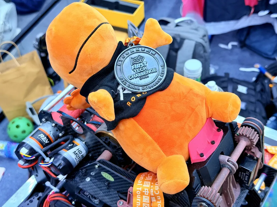 Team mascot wearing the FTC medal, sitting on the robot chassis in the pit
