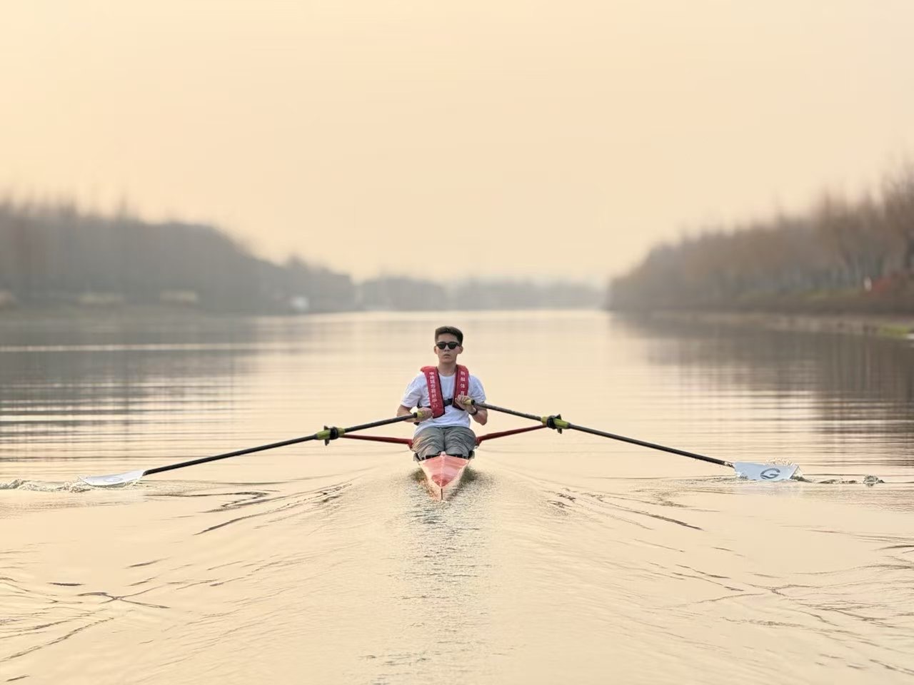 Solo sculler at golden hour — training on open water